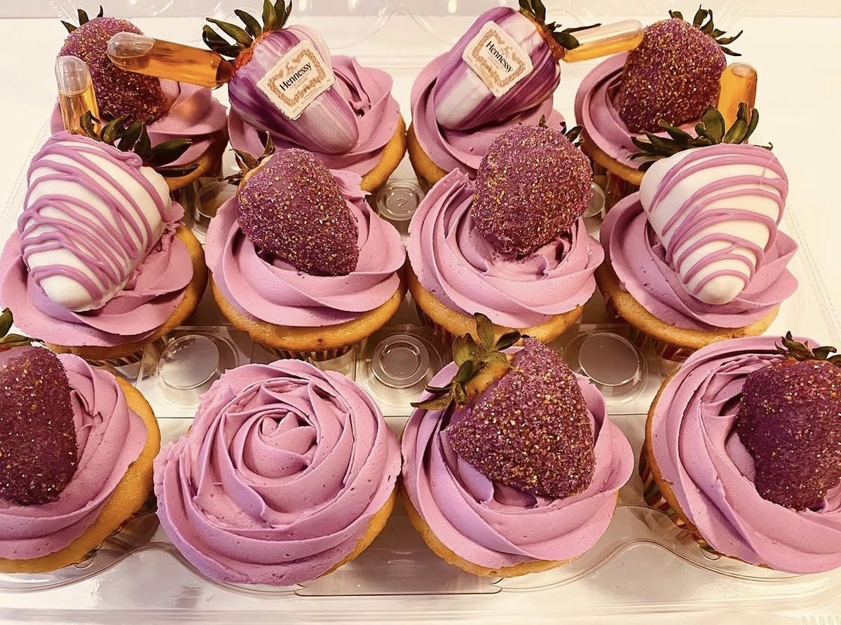 Tray of lavender buttercream rose cupcakes topped with glittered and white chocolate drizzled strawberries